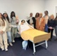 Image shows a group of women standing around a hospital bed