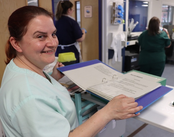 A member of hospital catering looking through a folder displaying information about swallowing difficulties