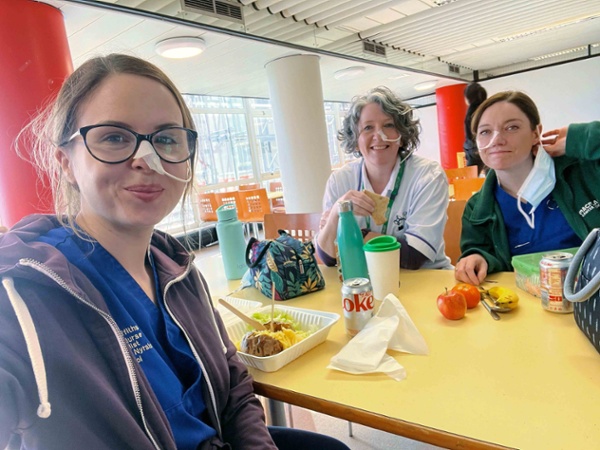 Image shows three hospital staff wearing nasal tubes while in the staff canteen