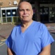 Image shows doctor in scrubs outside a hospital building