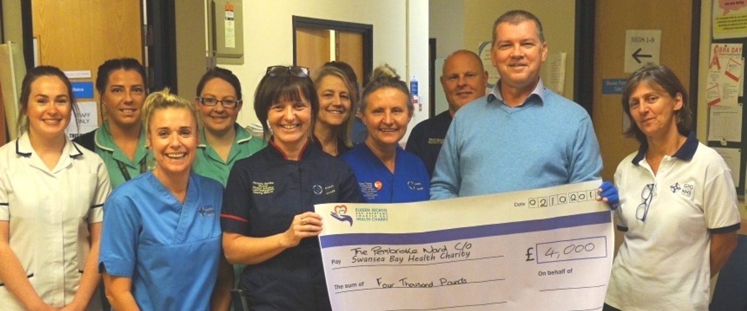 Former patient Ian Horsley gives a cheque to staff at the Welsh Centre for Burns and Plastic Surgery, Morriston Hospital.