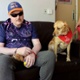 Image shows patient Jason sat on a sofa next to therapy dog Billie.