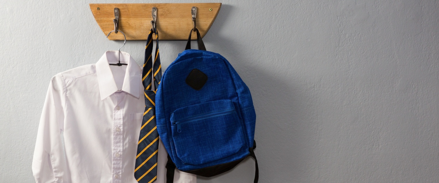 Image shows school shirt, school tie and bag hanging on hooks.