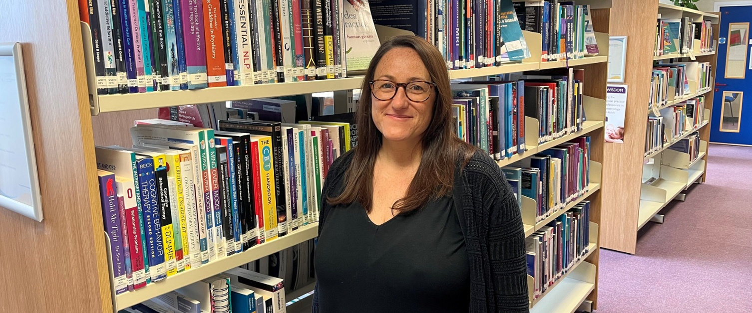 Image shows a woman standing in a library