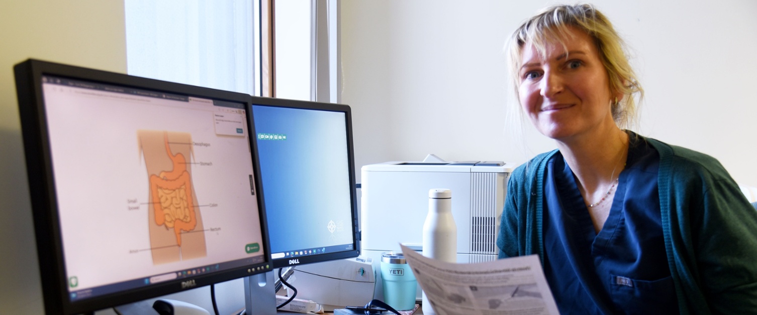 Dr Gemma Eccles holding a piece of paper next to a computer screen