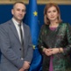 A smartly dressed man and woman standing in front of a European Union flag