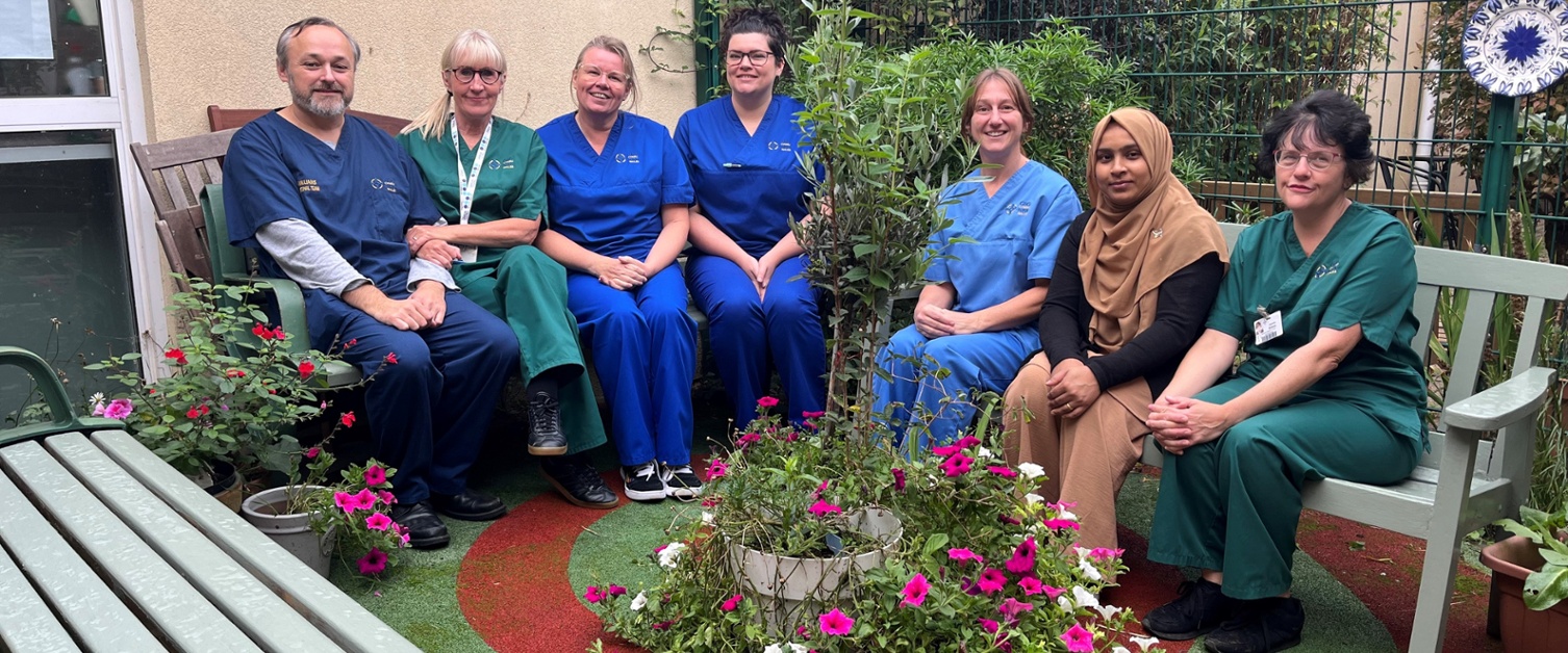 Image shows a group of people sitting in a garden