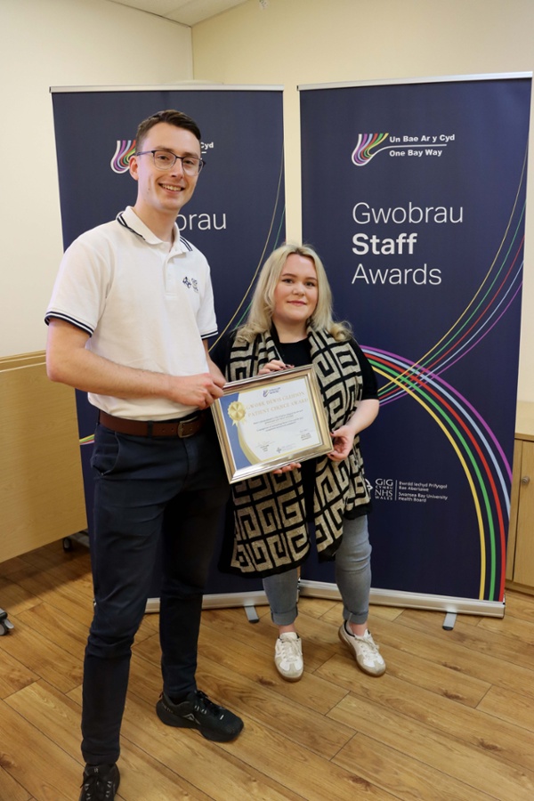 Image shows David and Jemma holding an award certificate and smiling