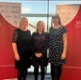 Three women stood at an awards ceremony
