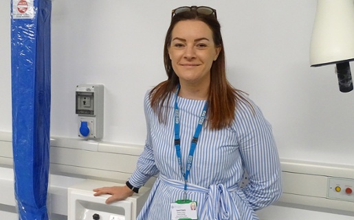 Image shows a smiling woman in a hospital ward.