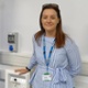 Image shows a smiling woman in a hospital ward.