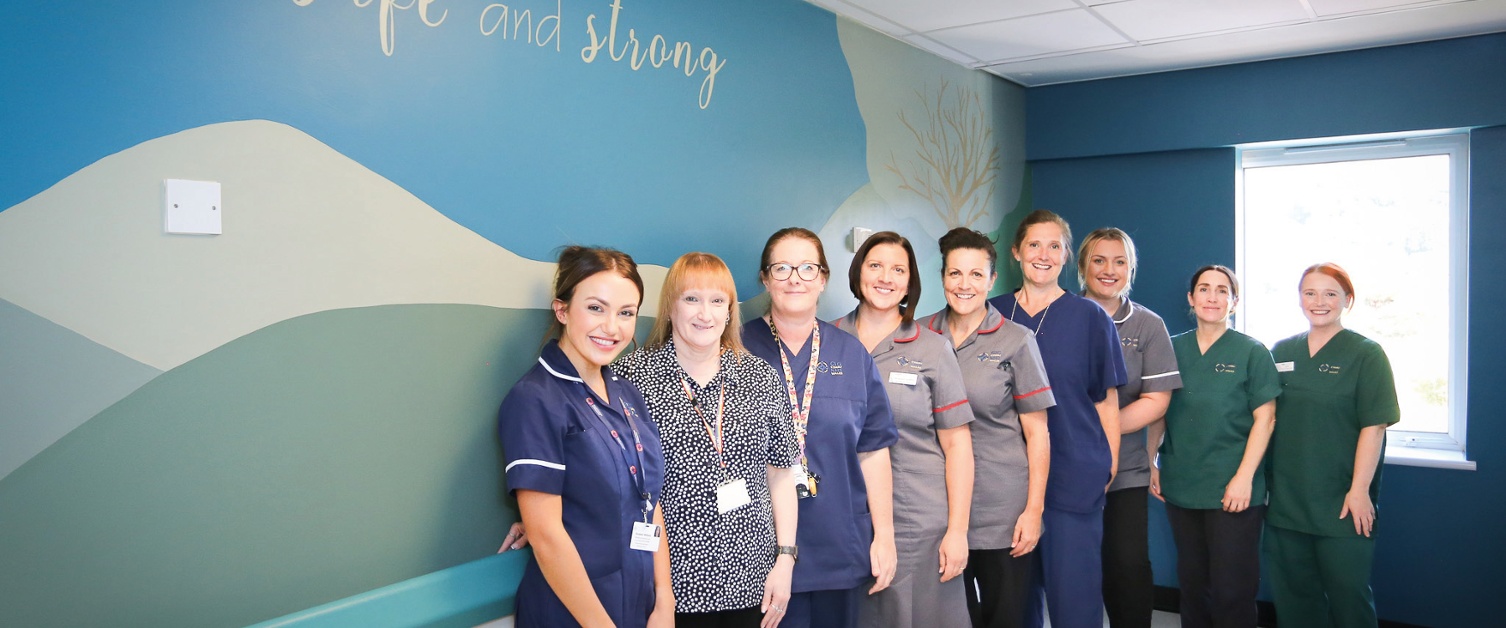 A group of midwives standing in front of a large wall mural