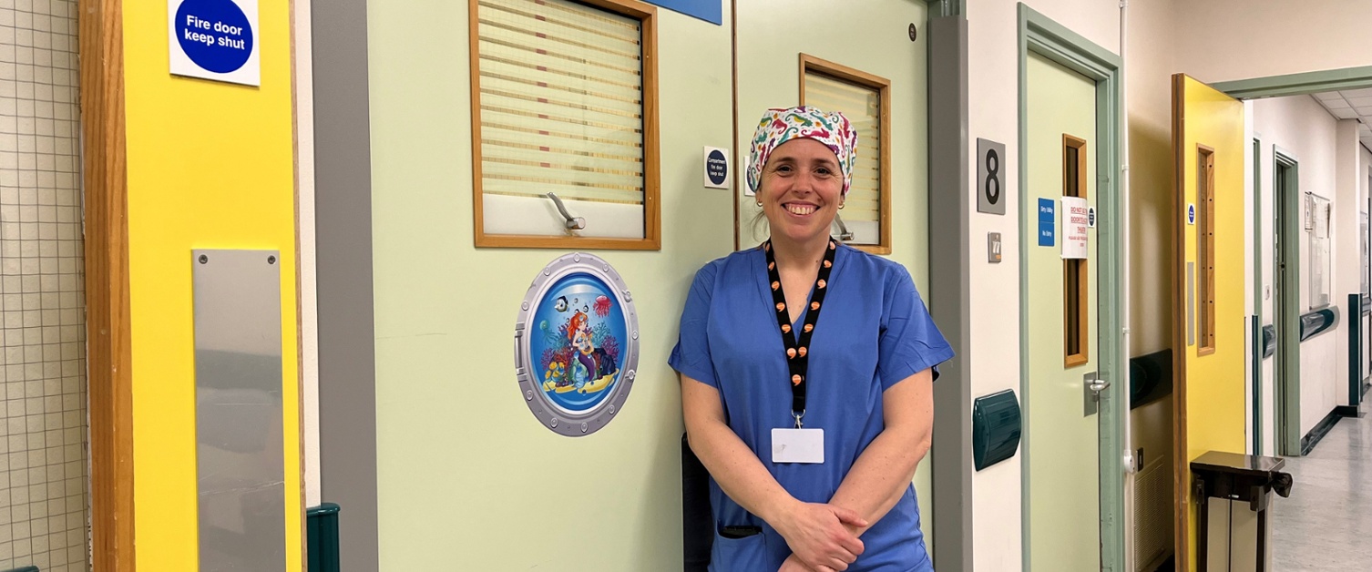 Image shows a woman standing in a hospital corridor