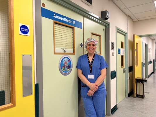 Image shows a woman standing in a hospital corridor
