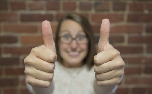 Woman smiling at camera with two thumbs up.
