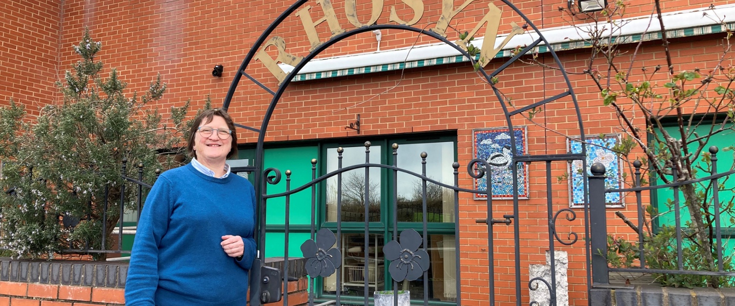 Image shows a woman standing next to a gate