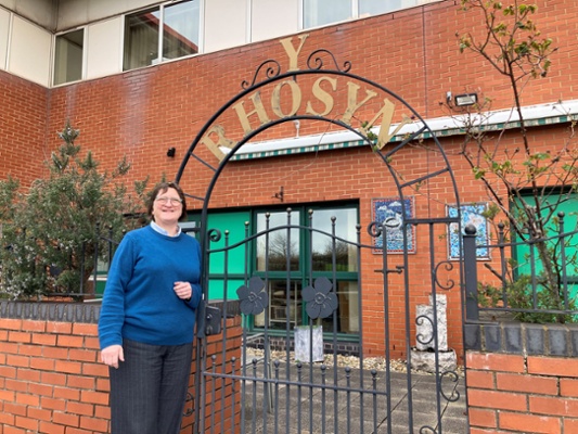 Image shows a woman standing next to a gate