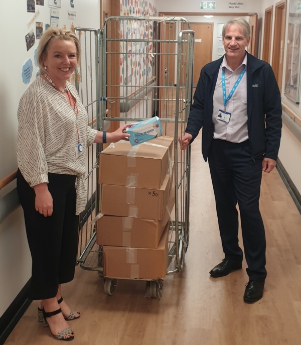 Image shows Deb Lewis and Mark Parsons next to a metal cage containing boxes of PPE.