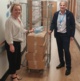 Image shows Deb Lewis and Mark Parsons next to a metal cage containing boxes of PPE.