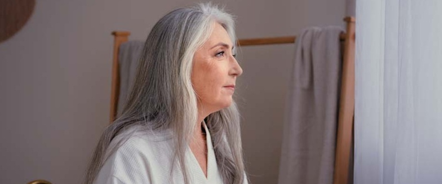A woman with long grey hair in a bathrobe.