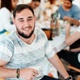 A smiling man. People behind him are painting around a table.