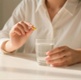 Image shows a person holding medication and a glass of water.