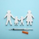Image shows paper cut out family and vaccination needle.