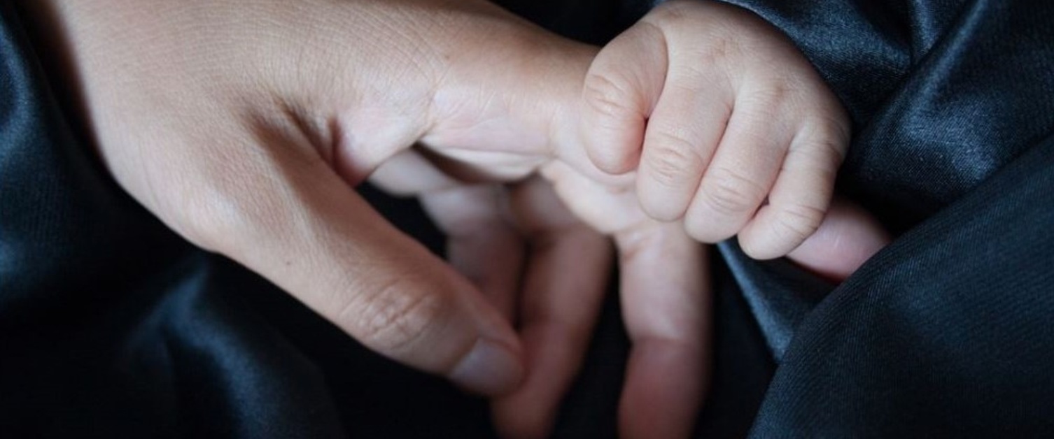 A mother and baby holding hands