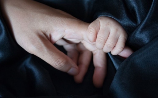 A mother and baby holding hands