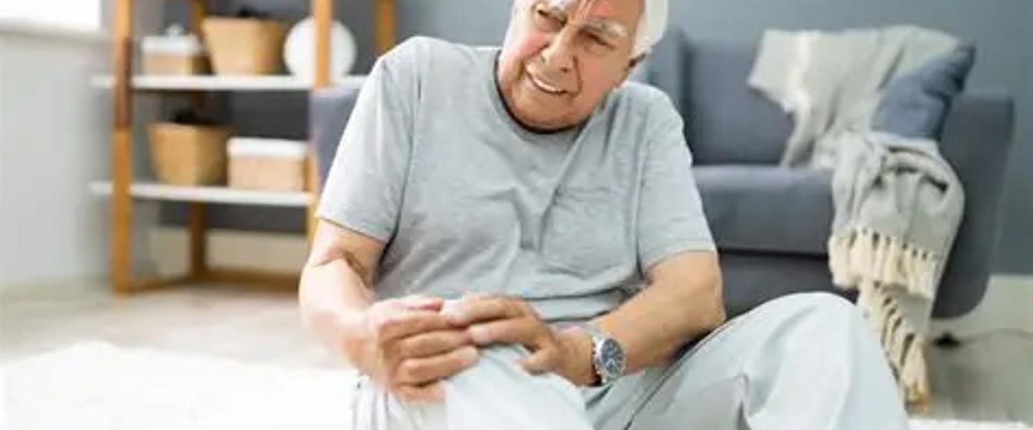 An elderly man holding his knee after falling
