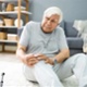 An elderly man holding his knee after falling