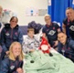 Image shows a group of people standing around a child in a hospital bed