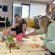 Isabel sat with a mum and baby on a mat