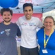 Three people smiling for a picture outside a charity stall