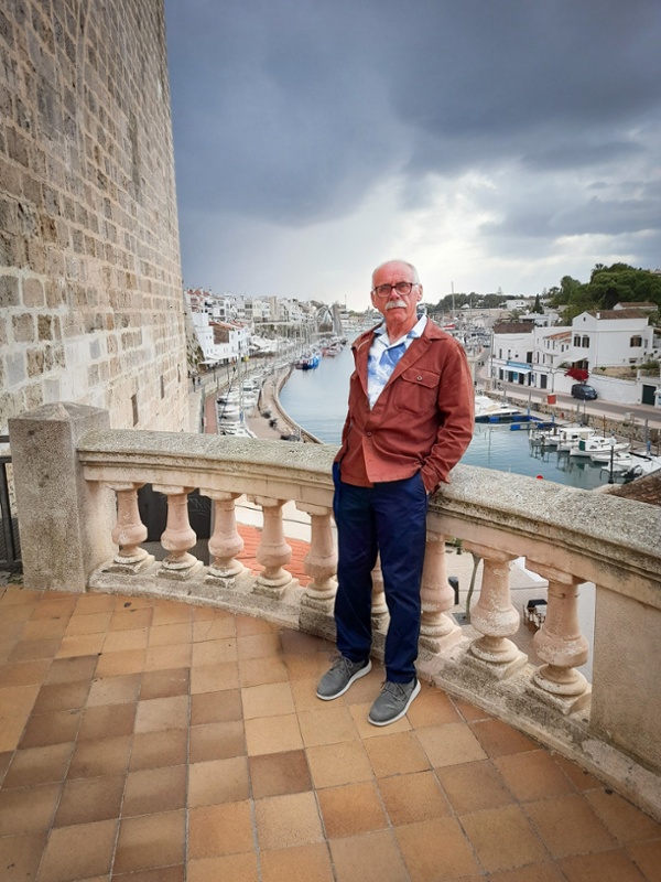 David yn sefyll ar falconi ar wyliau
