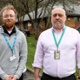 Aeron Jones yn sefyll wrth ymyl Howard Stevens y tu allan i adeilad yr ystadau.