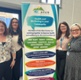 Llun o menywod yn sefyll y flaen arwydd Afan Cluster