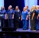 Pobl wedi gwisgo mewn gwisgoedd nyrsïa yn canu ar y llwyfan