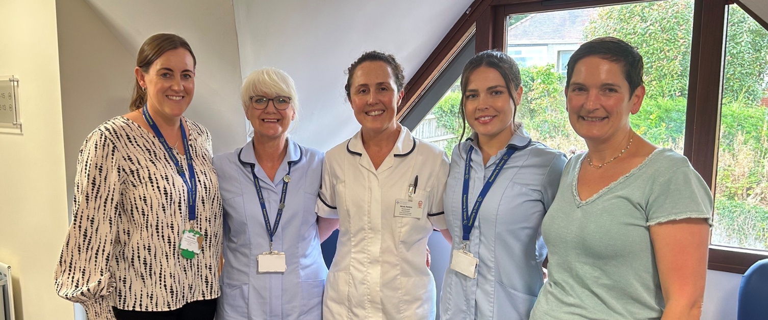 Aelodau staff yn sefyll mewn practis meddyg teulu