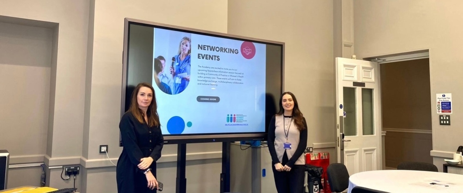 Rhian a Jess yn sefyll wrth ochr sgrîn deledu