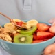 Hands holding a bowl of fruit and cereal / Dwylo yn dal powlen o ffrwythau a grawnfwyd