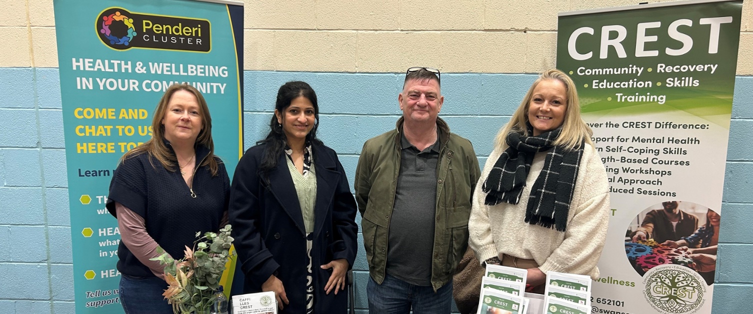 Anna, Sowndarya, Ian ac Alex yn sefyll o flaen desg