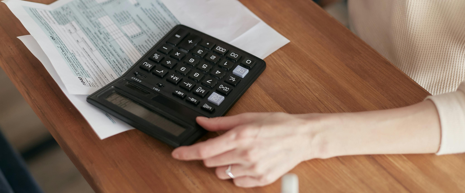 A person sat at a desk with a financial statement and a calculator