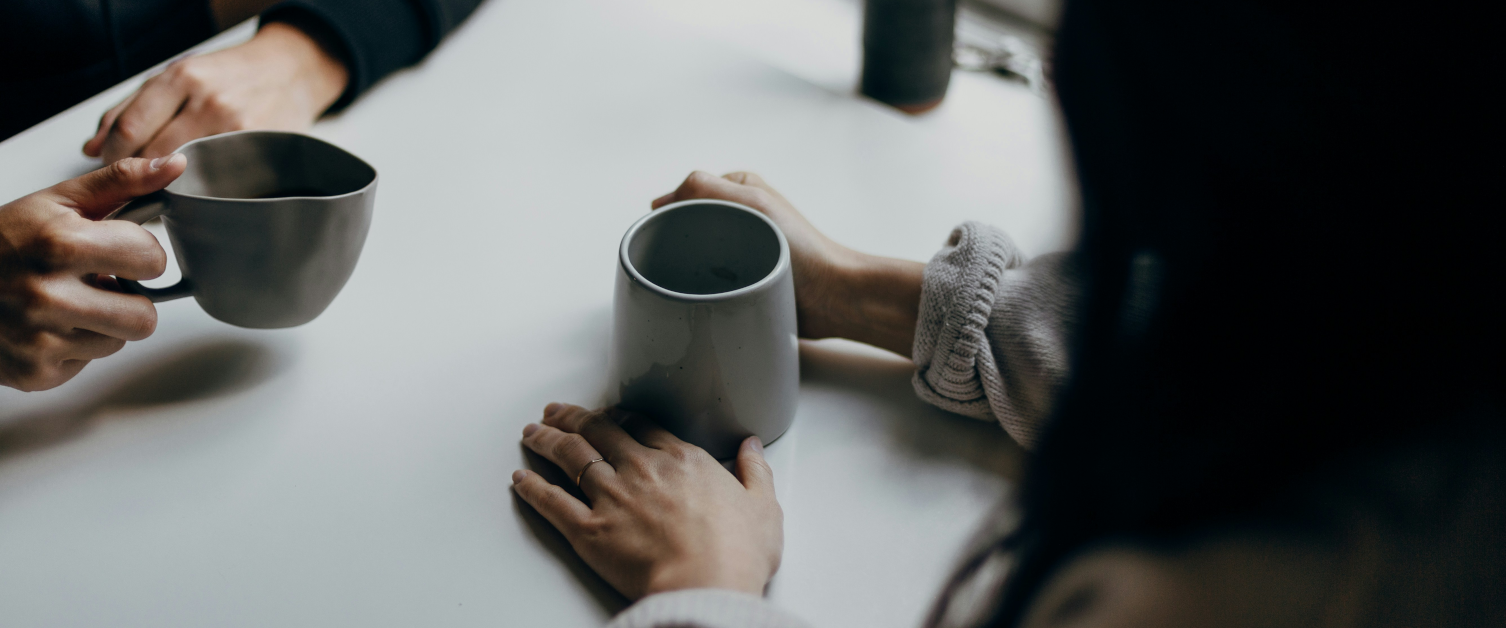 Two people sat at a table drinking coffee and chatting