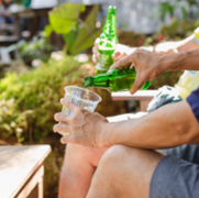 Men_pouring_bottle_of_beer_in_garden.png