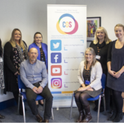 Some of the patient experience team huddled around a banner