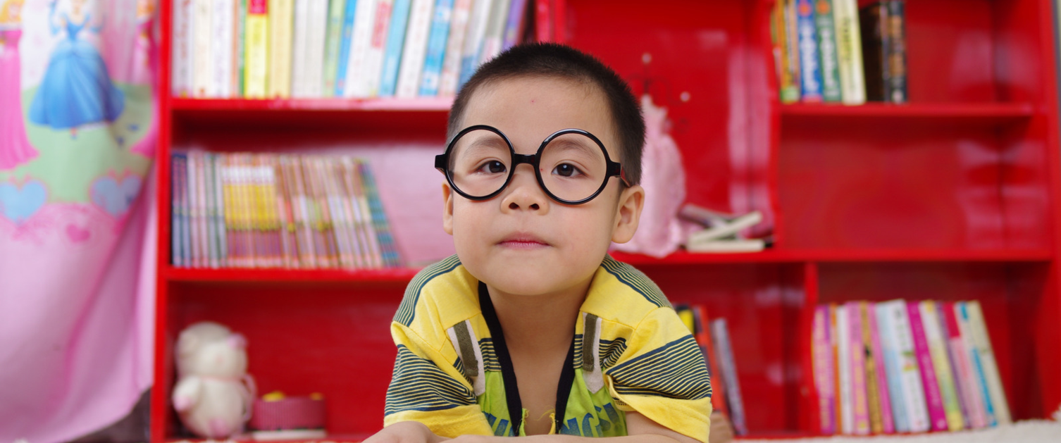 Boy reading by bookshelf