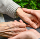 older person and younger person holding hands
