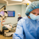 Surgeon in foreground while surgery takes place behind
