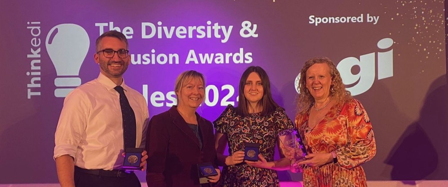 Jon, Katie, Lauren and Anne with awards - backdrop reads 